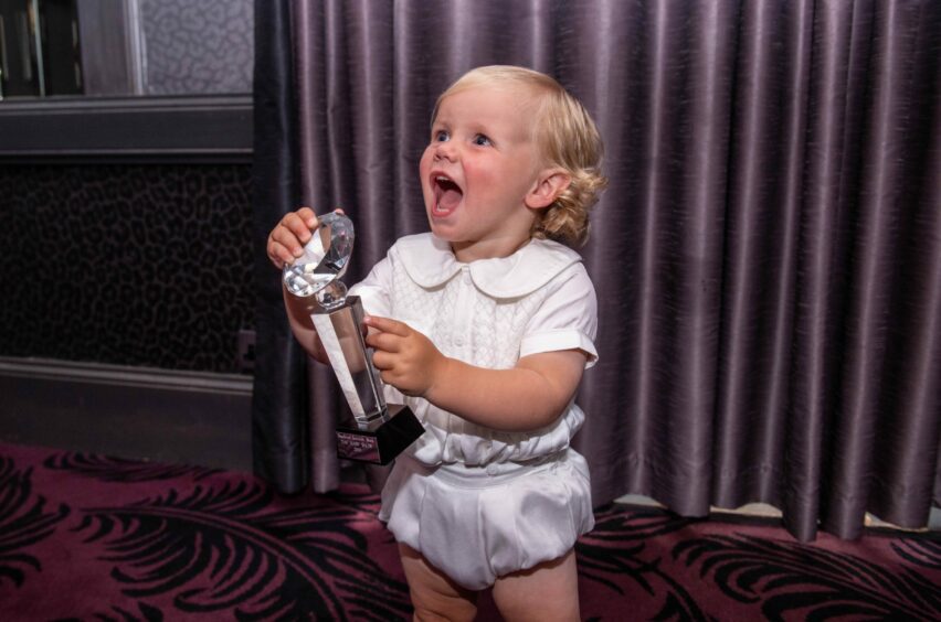 Young boy cheers after winning the Baby Show trophy at Peterhead Scottish Week.