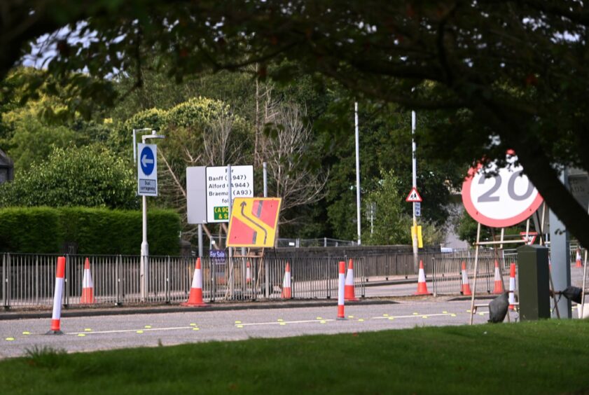 Roadwork signs and traffic cones on Aberdeen's Auchmill Road as roadworks begin.
