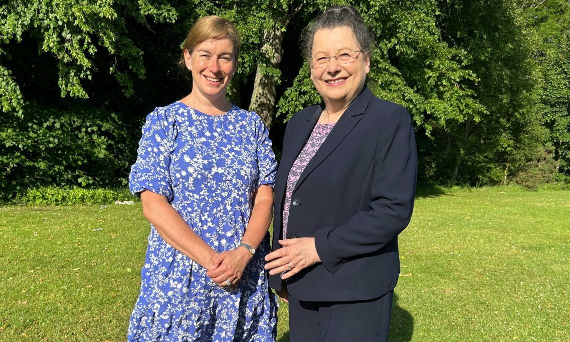 Moray Council leader Kathleen Robertson and Ann Rossiter in a green park with bushes behind. 