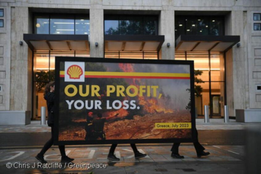Greenpeace protesters erect a giant spoof billboard outside Shell's HQ