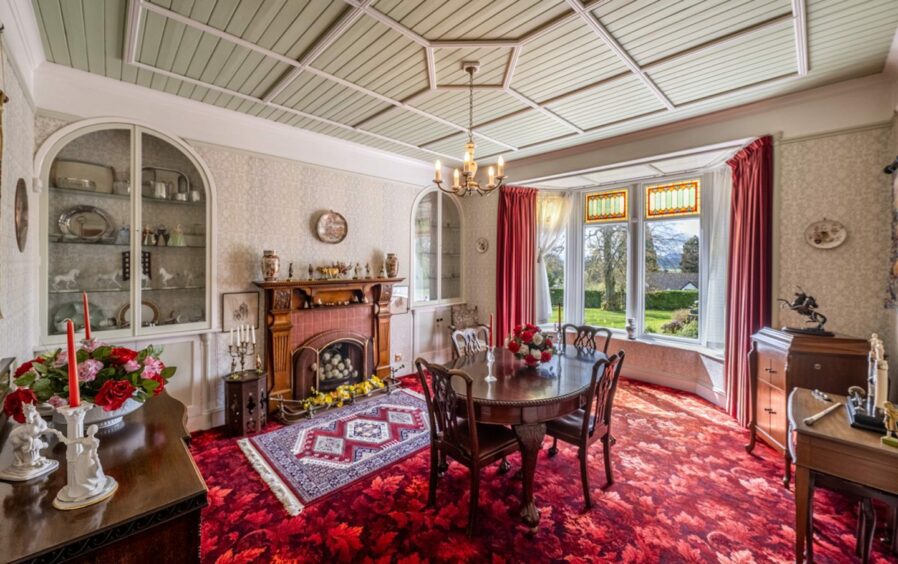 Dining room inside the home in Torphins with red carpetting and wood fireplace.