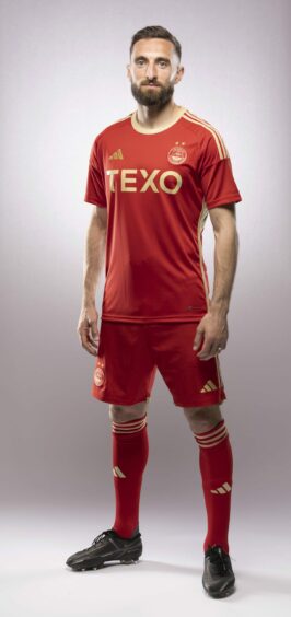 Graeme Shinnie in Aberdeen's new 23/24 home kit, which is red with gold accents.