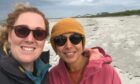Bethany Graves and Roma Banga wearing sunglasses on a windswept Tiree beach.