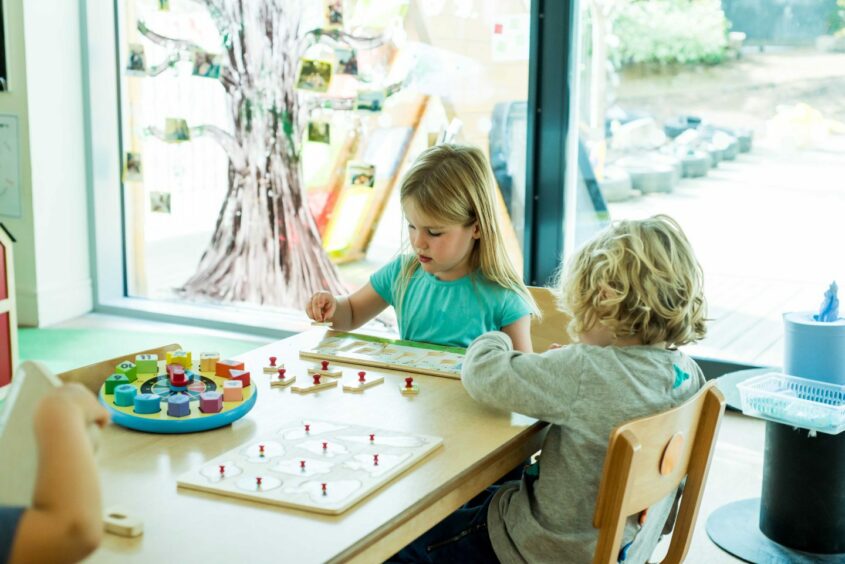 Two pre-school students play with a puzzle while sat at a desk at ISA.