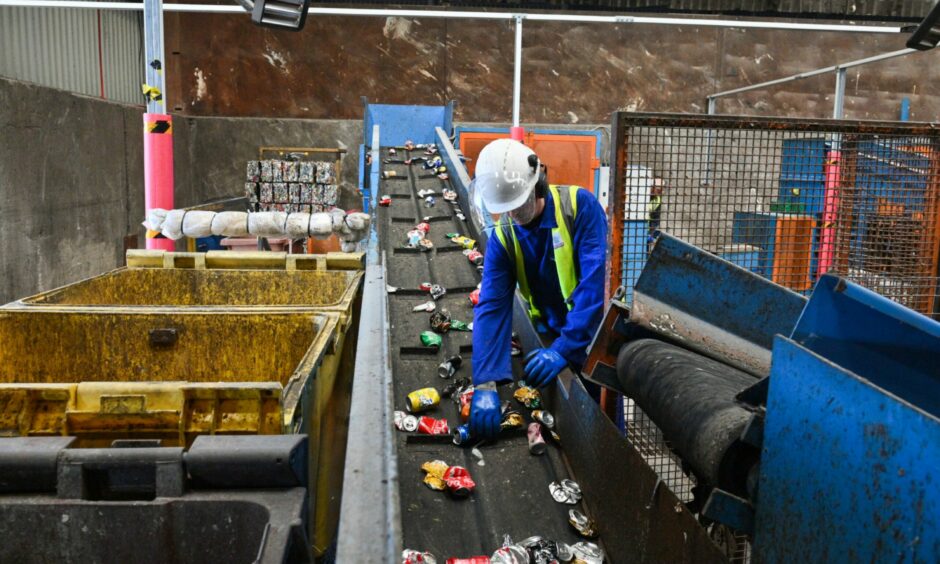 A waste management worker picking out items that cannot be recycled from the conveyor belt.