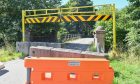 Orange barriers block access to the road bridge.