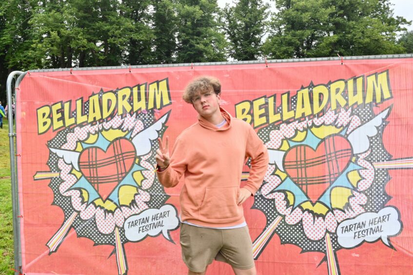 Boy poses in from of Belladrum Tartan Heart Festival signage.