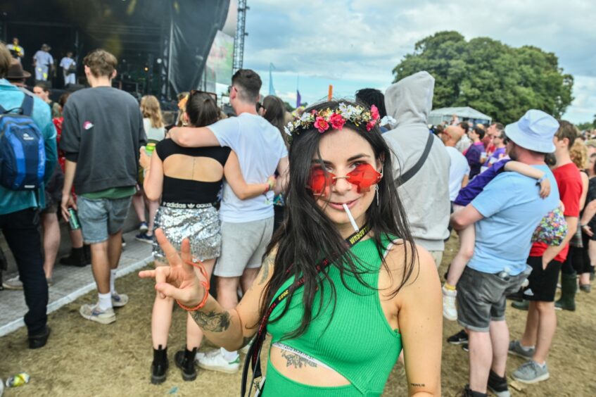 Young reveller with red sunglasses and flower crown.
