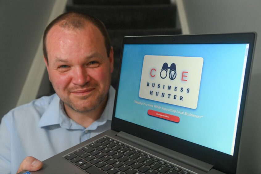 Ryan Coutts holding a laptop with the Cove business website, Cove business hunter on the screen