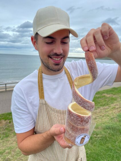 Pavel unravelling a chimney cake at Aberdeen beach.