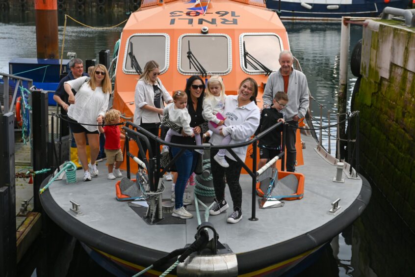 Family smiles for pictures on lifeboat.