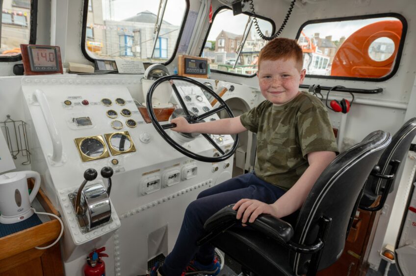 Young boy at the lifeboat's wheel.