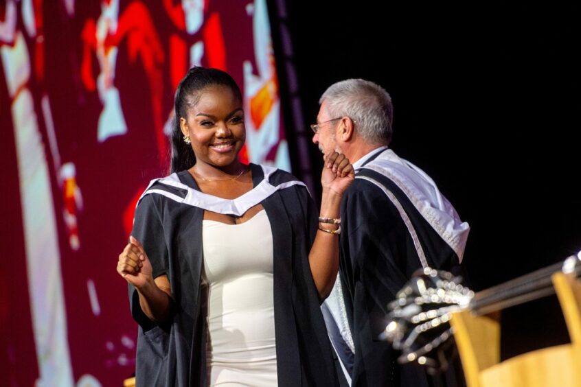 A proud graduate dances on stage at their graduation.