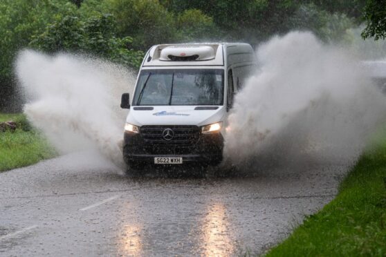 A van splashing through a large pool of water on the road. Heavy rain has been forecast across Aberdeenshire, Argyll and the South Highlands.