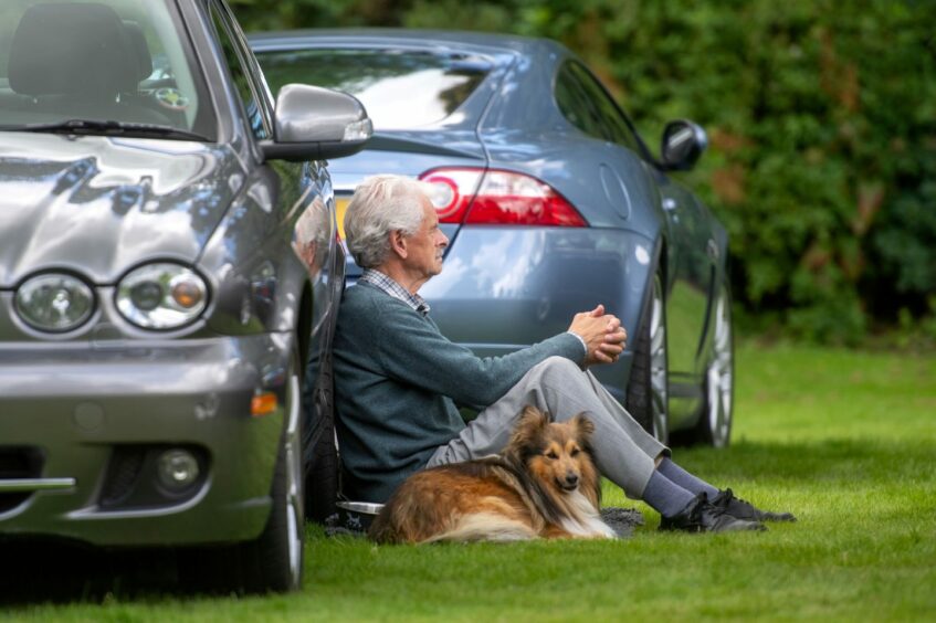Man sitting on grass with dog.