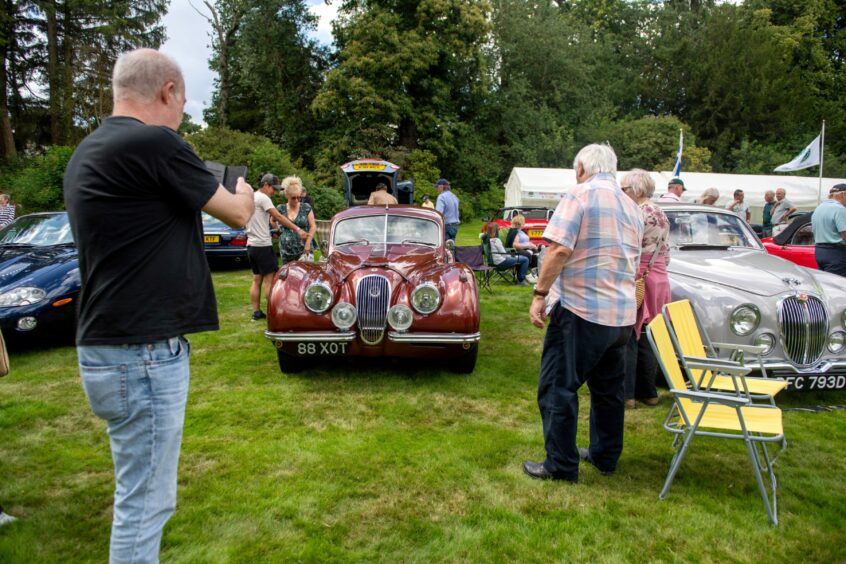 Car enthusiasts take pictures of the vehicle on display at the Annual Gathering and Car Show at Drum Castle 2023.
