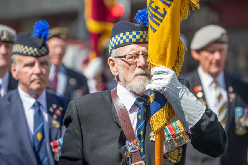 A man in uniform carrying a flag during the parade.