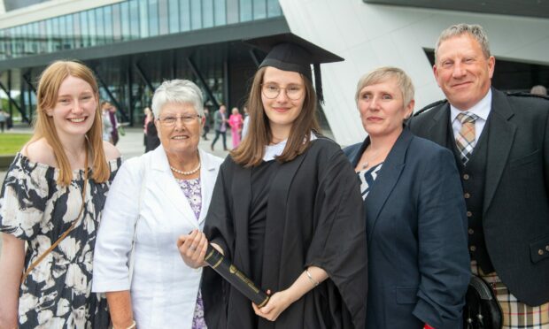Proud graduate poses for a photo with loved ones. Image: Kami Thomson/DC Thomson