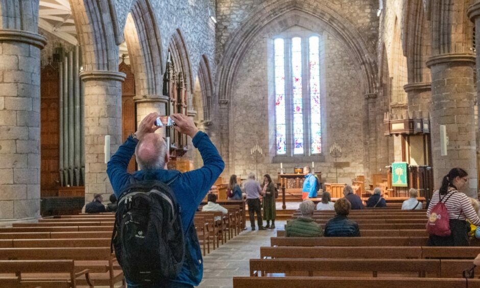 A cruise ship tourist taking a picture of St Machar Cathedral in Old Aberdeen.