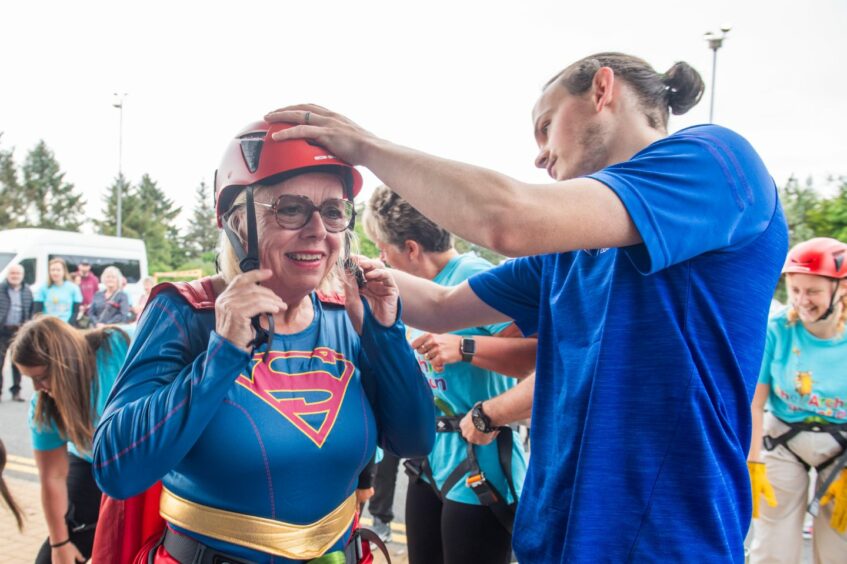 Jackie McIntyre wearing a Superwoman uniform putting her helmet on