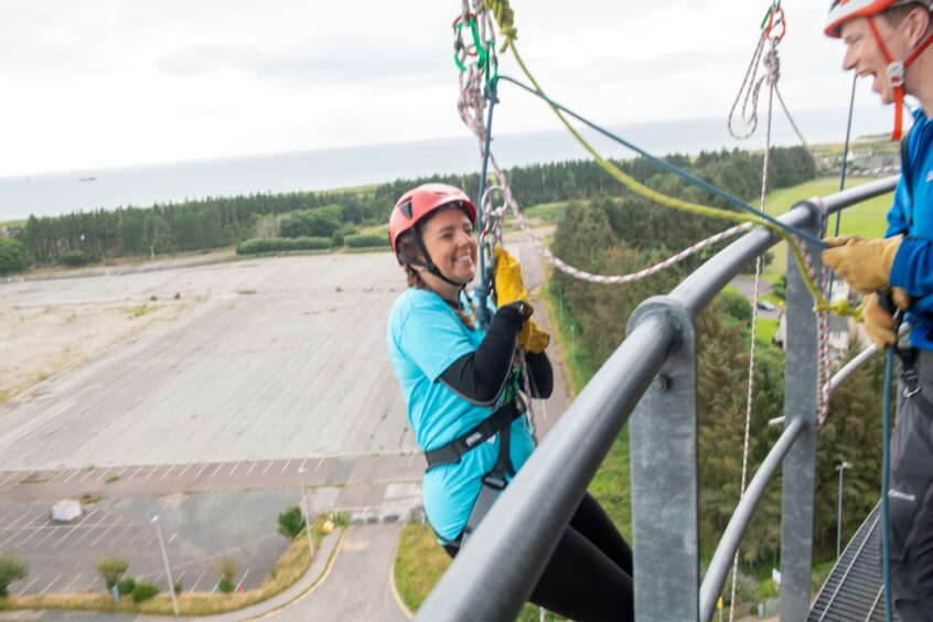 A woman at the top of the abseil tower