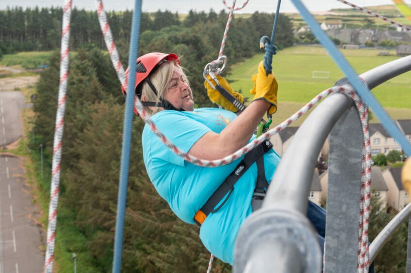 A woman leans off the barrier in her abseil gear
