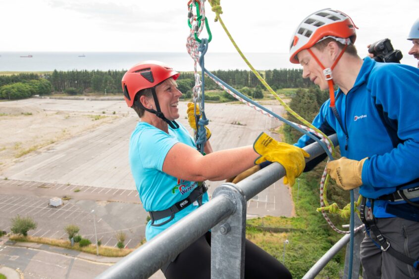 A woman holding on to the tower barrier before abseiling 