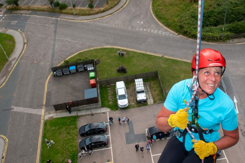 A woman smiles as she begins the abseil 
