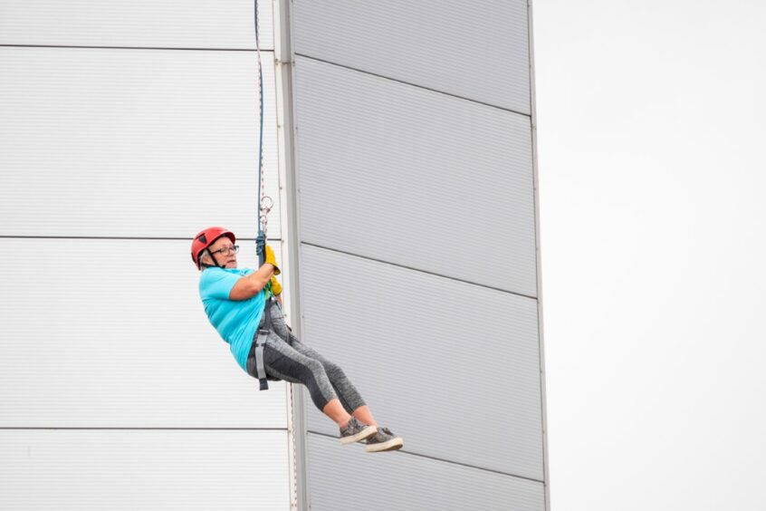 A woman abseiling down the tower 