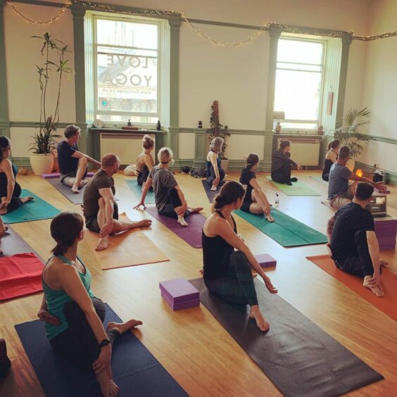 people sit on mats as they take part in a yoga session in Aberdeen's Love Yoga