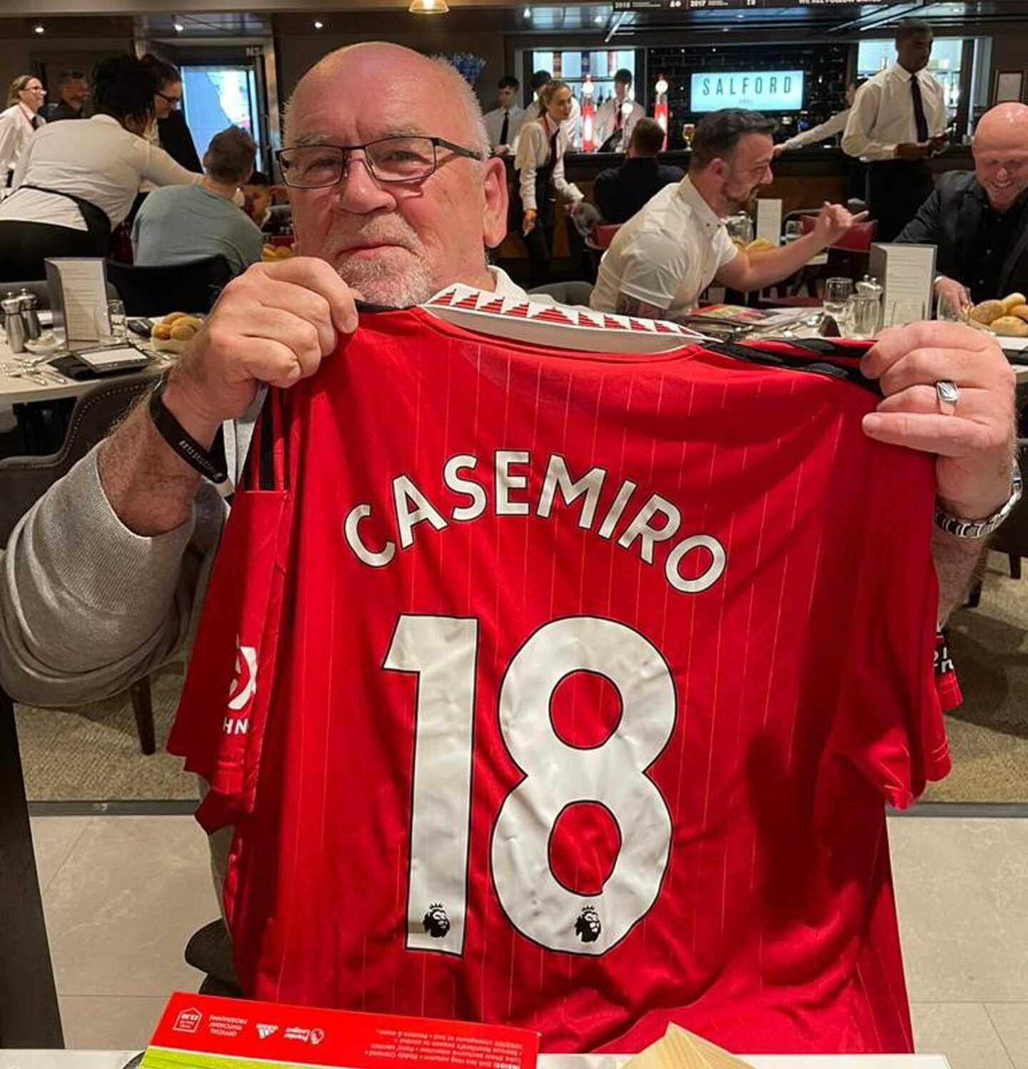 Malcolm Ritchie holding up a Manchester United shirt with Casemiro 18 on the back. 
