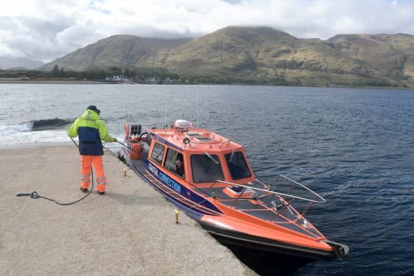 A small orange passenger vessel docked at the Corran ferry crossing.