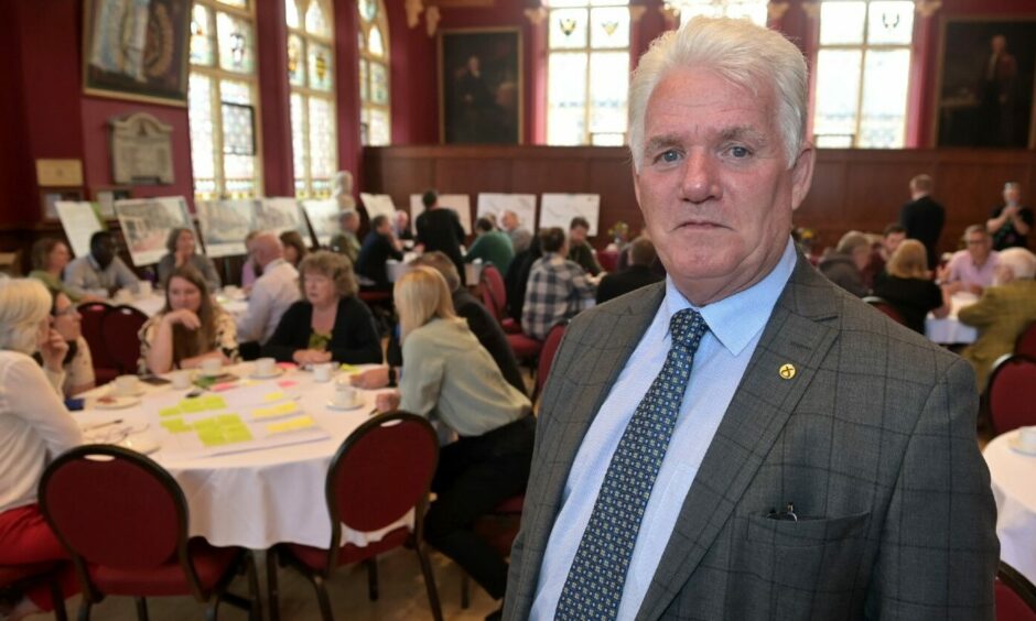 Councillor Ian Brown at a meeting in Inverness Town House with people behind.