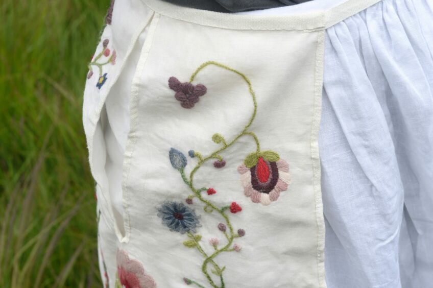 The pocket tied around the models waist. the fabric has flowers embroidered on it