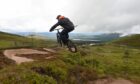 A mountain biker in mid air over a jump.