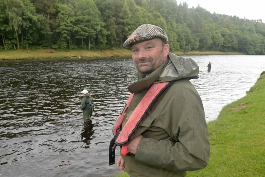 Simon Crozier, senior ghillie at Castle Grant Fishing's, watches on as a young angler fishes in the background. 