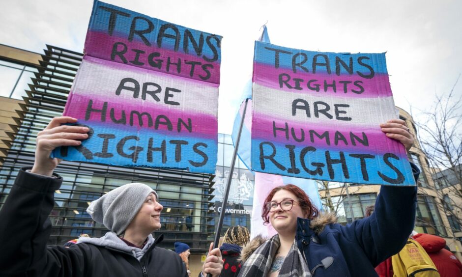 Two individuals at a trans rights rally holding signs that read: "Trans rights are human rights"