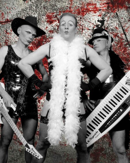 The Bloody Marys band members wearing dresses, thigh-high fishnets and a feather boa.