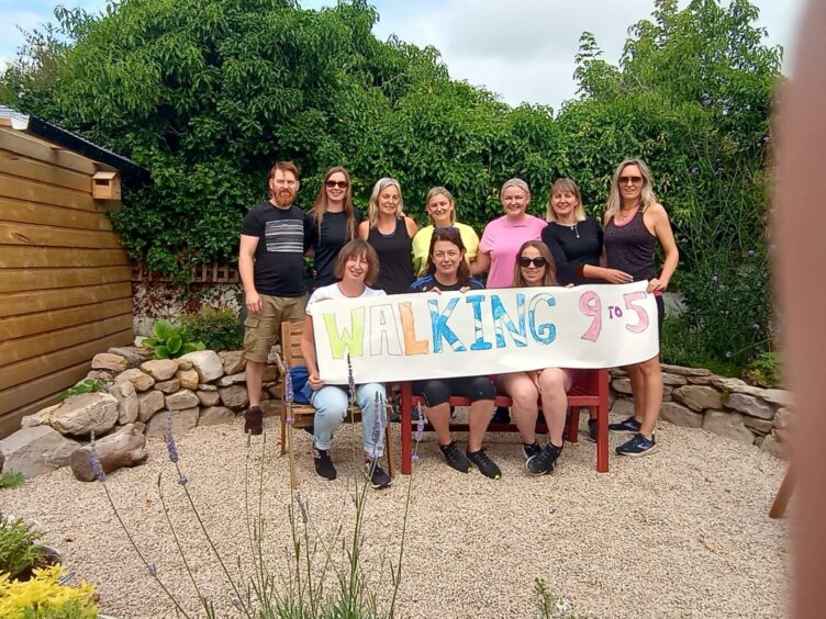 The team in Ireland who joined the fundraising effort for Aberdeenshire mum Julie Williams, holding a sign for their Race for Life group 'Walking 9 to 5'.