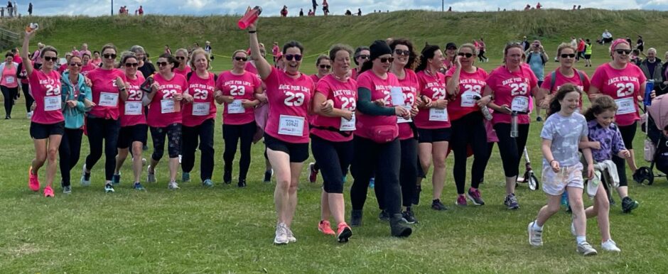 The Walking 9 to 5 team cross the finish line at the Race for Life in Aberdeen, led by Julie Williams’s daughter Lucy. 