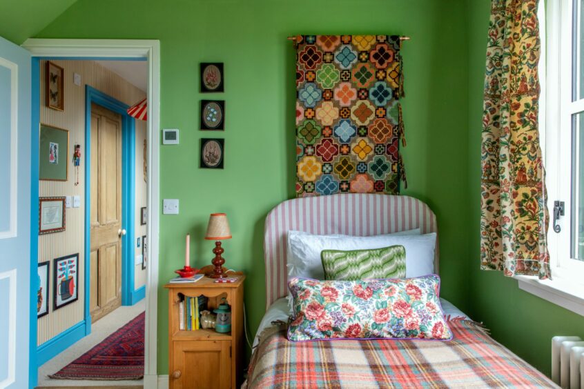 One of the bedrooms featuring green walls and colourful wall art and decor.