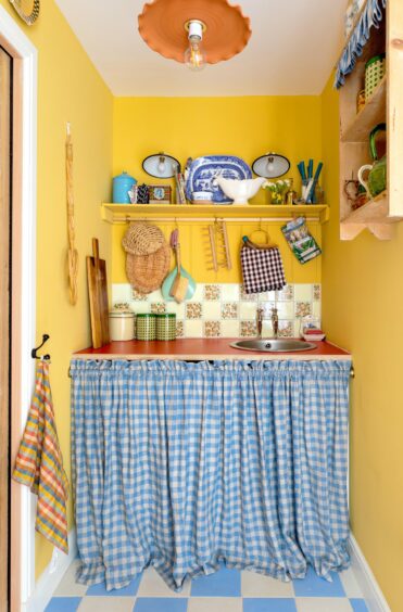 Kitchen pantry with yellow walls and blue gingham curtains.