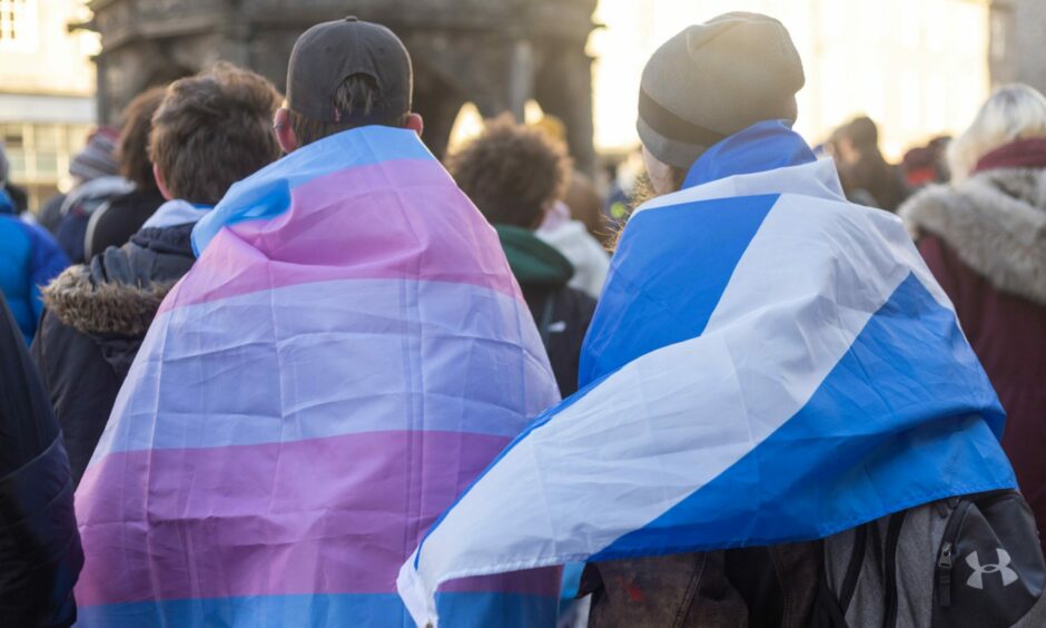Person wearing a transgender flag stands with another wearing a saltire at a trans rights rally in Aberdeen.