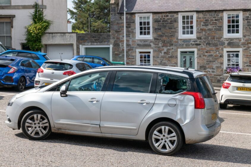Silver car with smashed back window and dent on side following crash in Cullen 