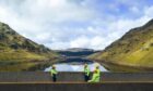 Three SSE Renewables employees in high vis coats stood in front of Sloy Power Station.