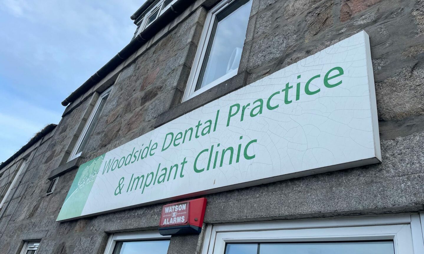 The green and white sign above the Woodside dental practice & implant clinic