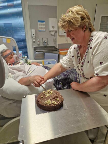 The couple cutting a cake in hospital.