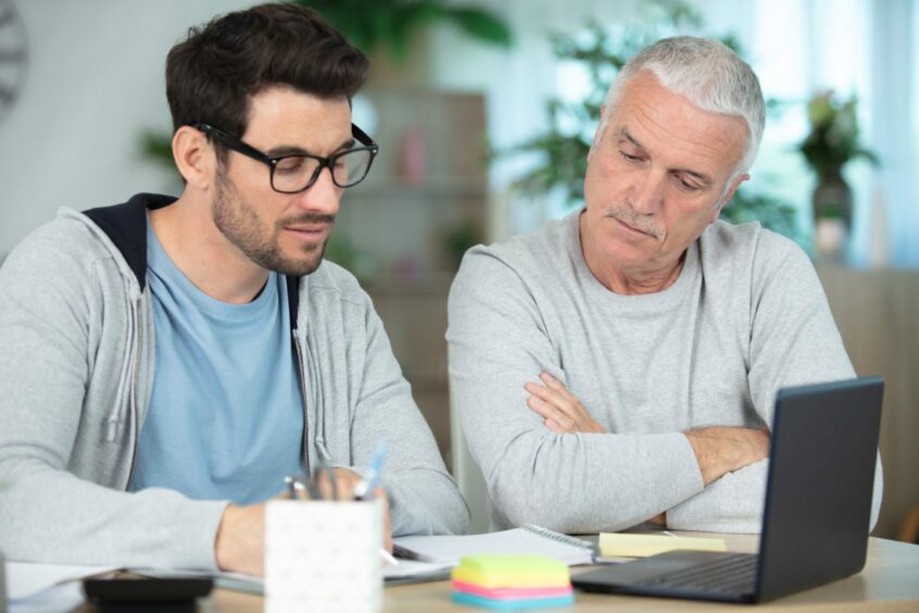  A young man and his dad look over some money matters.