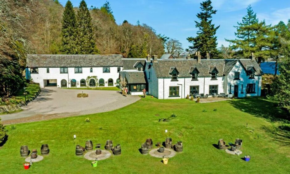Exterior of Taychreggan Hotel surrounded by lush greenery.