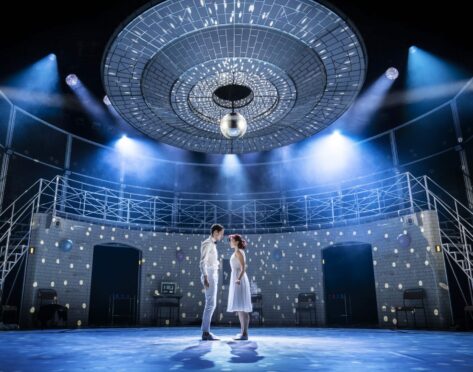 Romeo and Juliet stand together under the light of the disco ball.